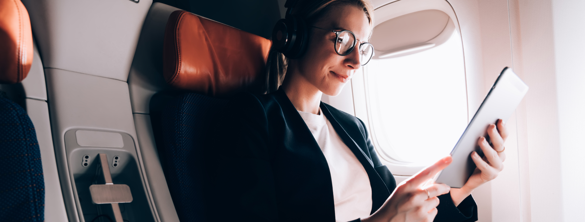 A woman sitting on a plane with her tablet